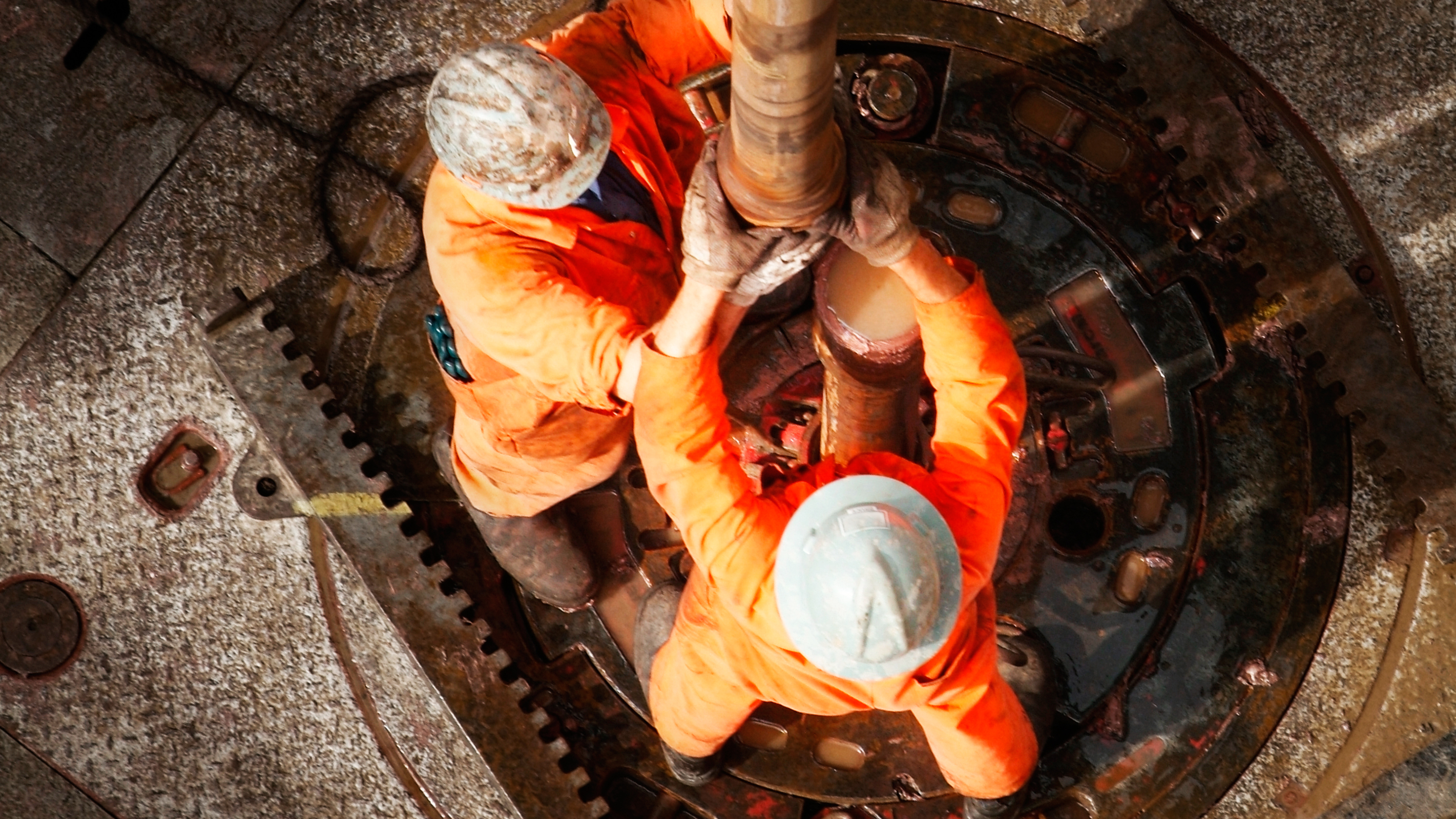 Hommes en combinaison de travail orange et casque dans une installation industrielle